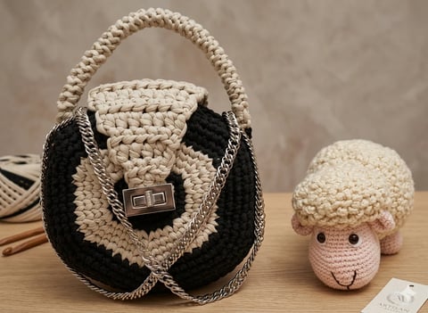 Handmade crocheted items: cream knitted handbag with black accents and handle, alongside a cream sheep figurine with brown details